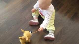 Baby tries feeding snacks to mechanical dog