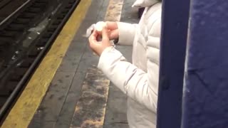 Woman white jacket eating egg subway platform