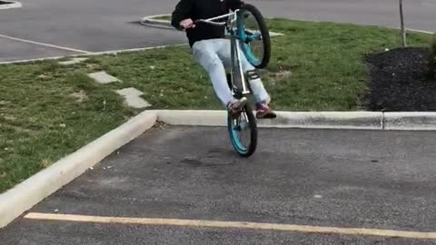 Guy does a wheelie over grass curb and falls backwards