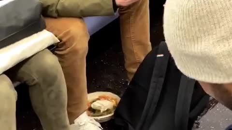 Guy sets his bowl of food on subway floor to text on his phone