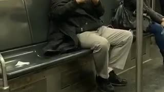 Man wearing beret plays his flute alone in a subway train