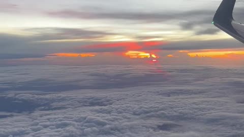 Window View from an Airplane Flying above the Clouds