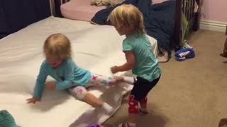 Identical twin toddlers tickle each other