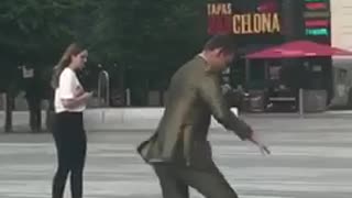 Guy in suit tries to ride skateboard and falls onto pavement