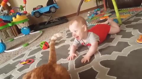 THE BABY IS PLAYING WITH THE CATS TAIL