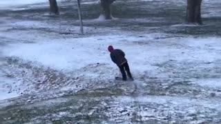 Kid rides blue scooter down snow covered hill and faceplants