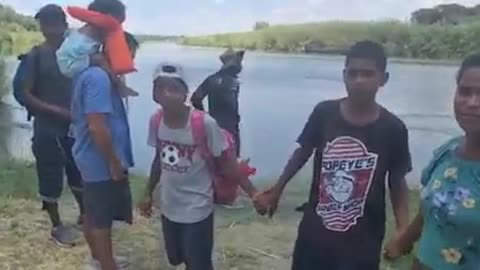 Migrants hold hands and entrust themselves to God before entering North American territory