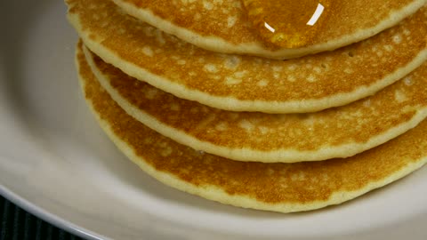 Honey pouring over pancakes