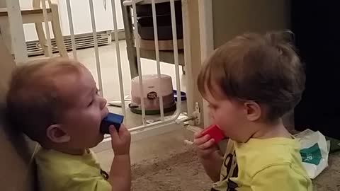 Twin brothers adorably share toys