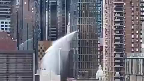 Massive cascade of water pouring down side of tall building in Manhattan, New York City