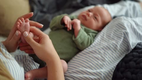 A mom is smoothing her baby's tiny foot!