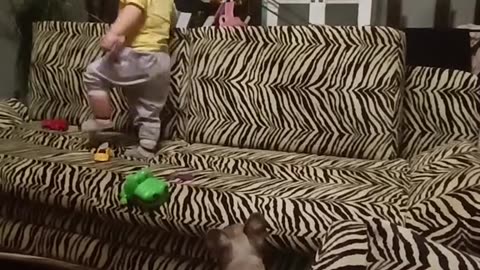 A boy helps his puppy climb onto the sofa