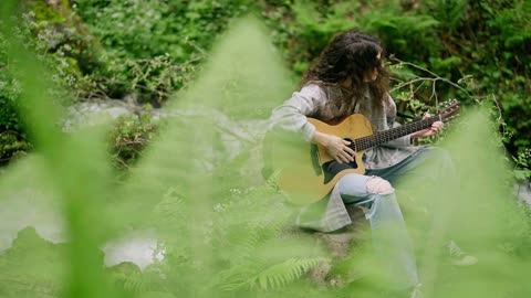 A Woman Playing the Guitar by the River