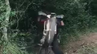 Dirt biker rides on dirt trail and flips over his bike
