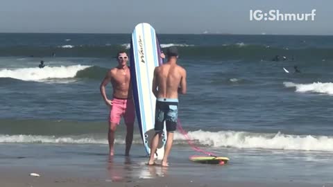 Two guys with surf boards taking selfies on beach