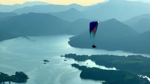 a person who paraglides on high mountains overlooking the lake