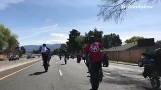 Motorcycle white helmet tries to kick leg during wheelie falls off