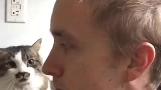 Blonde guy sits with white grey cat