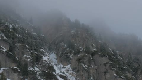 Snow falling by a mountain side