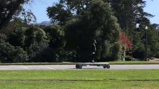 Girl at golden gate park rides a huge motorized skateboard