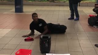 Man in black outfit red beanie dancing subway station