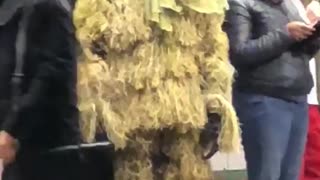 A person dressed like a tree on subway platform