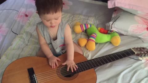 Cute little boy is playing guitar