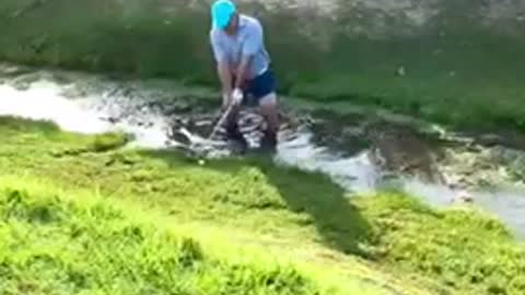 Golfer attempting shot out of creek