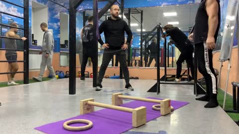 Man Holds A Planche By Balancing Rings On Parallettes