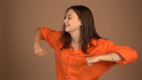 A Woman In Orange Shirt Is Dancing Happily