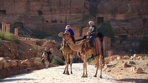 People rides on a camel near Temenos Gate and along The Colonnade Street in Petra