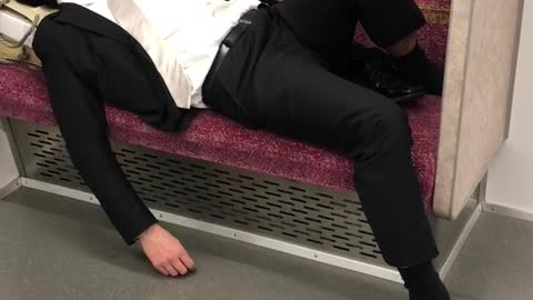 Man in suit asleep on red subway train seat