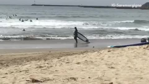 A man dragging a surf board on the beach