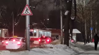 Elderly Woman Slowly Leads Tram Down the Road