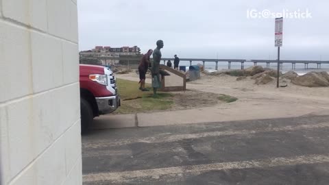 Homeless man throws things at statue at beach