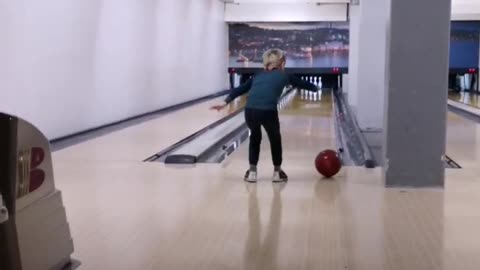 Little boy drops red bowling ball gutter