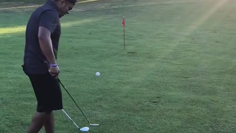 Guy juggles golf ball on golf club then uses other golf club to swing and hit ball