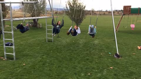 Four girls back flip on swings one falls