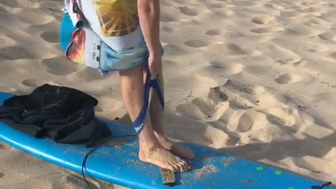 Guy blue surfboard sand beach guy trying to put on underwear windy towel