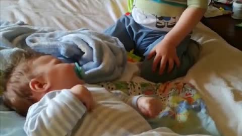 Brother is cuddling little baby, and gives a pacifier to her