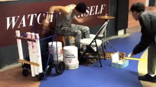 Guy plays the drums like crazy in subway station using containers, chairs, and wall