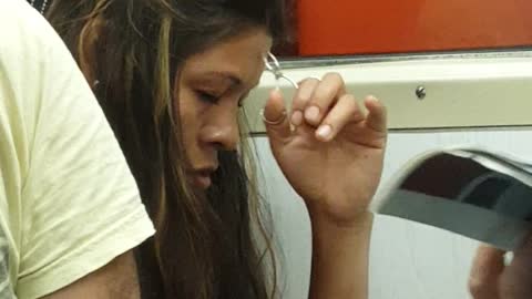 Woman sleeps and plucks her eyebrows with tweezers on subway train
