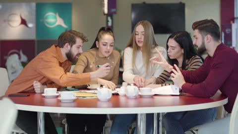 Students in a cafeteria discussing an assignment