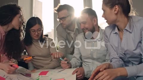 Group Of Coworkers Making A Banner And Talking To Each Other In The Office