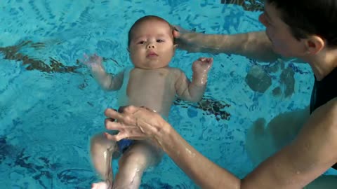 Little baby learning to float in the pool water