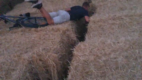 Guy rides bike on hay and falls face first