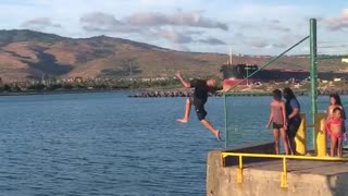 Guy parkour runs off of dock pier and into water front flip