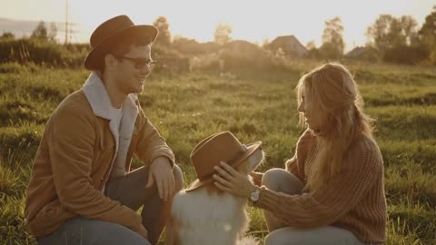 Portrait of young married couple of millennials on walk in field with dog or puppy