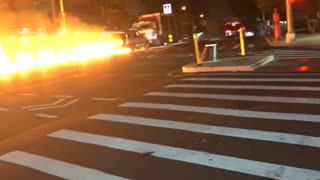Car Pushes Flaming Motorcycle down Street