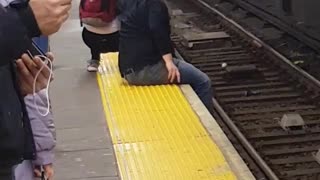 Couple hang feet off subway terminal and get up awkwardly